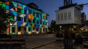Climate controlled projector enclosure mounted on truss for building projection mapping on an outdoor facade.