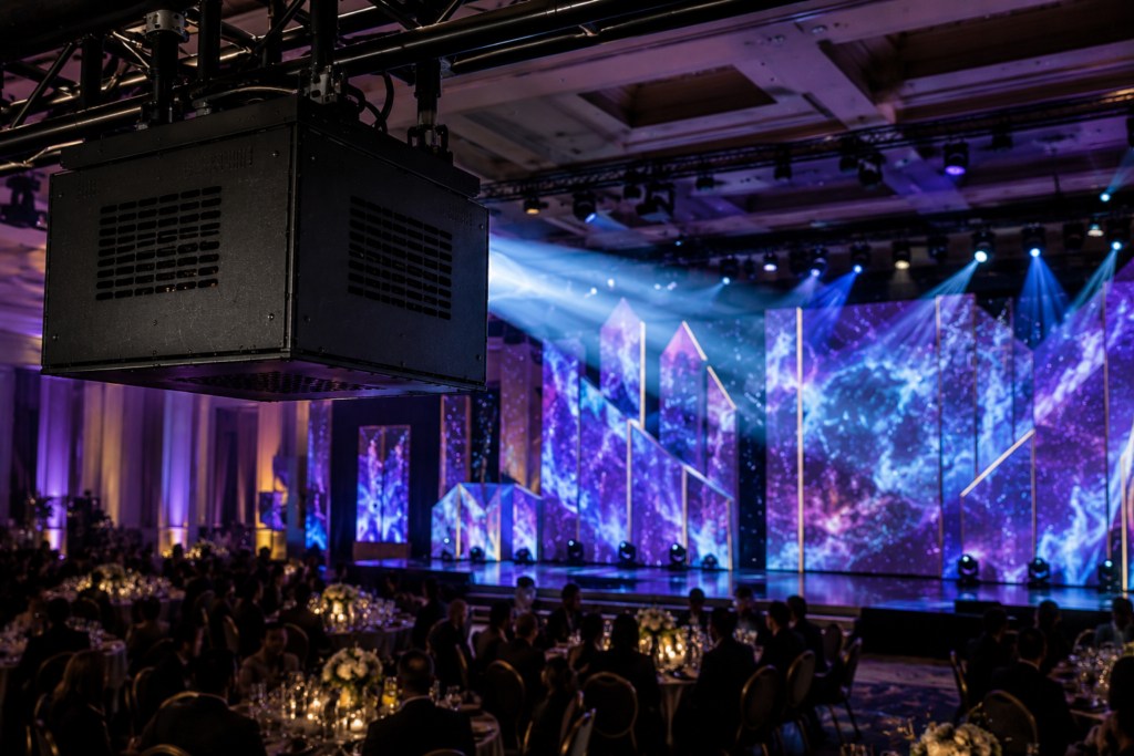 Fan-cooled projector enclosure used for event projection mapping with the projected stage as the main focus.